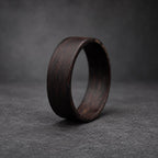 A dark brown wooden ring with a smooth, polished finish. The ring is thick and has a wide band.