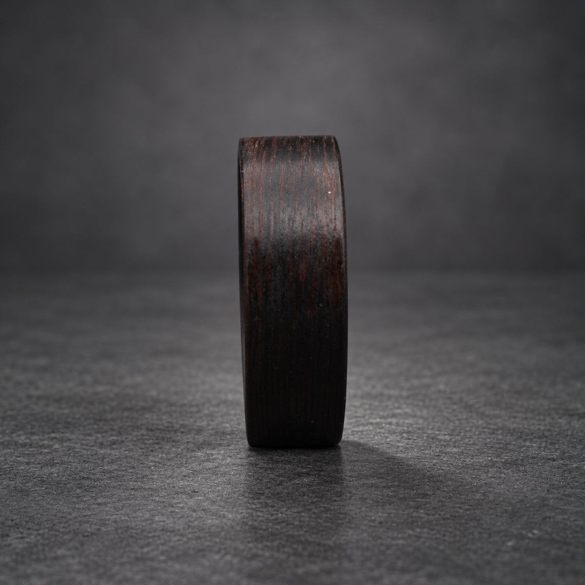 A black wooden ring with a dark brown wood grain pattern.