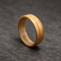 A close-up of a wooden ring with a natural wood grain finish. The ring is made of multiple layers of wood, creating a unique and interesting pattern.