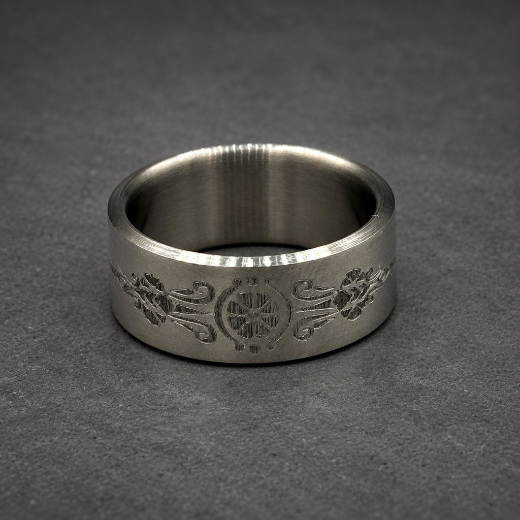 A silver ring with an engraved floral and geometric pattern. The ring is wide and has a smooth, polished finish. The design is centered and symmetrical.
