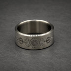 A silver ring with an engraved floral and geometric pattern. The ring is wide and has a smooth, polished finish. The design is centered and symmetrical.
