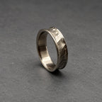 A silver ring with a textured, hammered finish. The ring has an irregular shape and a band approximately 0.6 cm wide. The surface has a rugged, industrial aesthetic, with visible hammer marks.