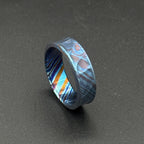 A patterned ring in shades of blue, purple, and orange. The ring's design is intricate and eye-catching, with a modern aesthetic. The ring is suitable for everyday wear or special occasions, with a unique and stylish appearance.