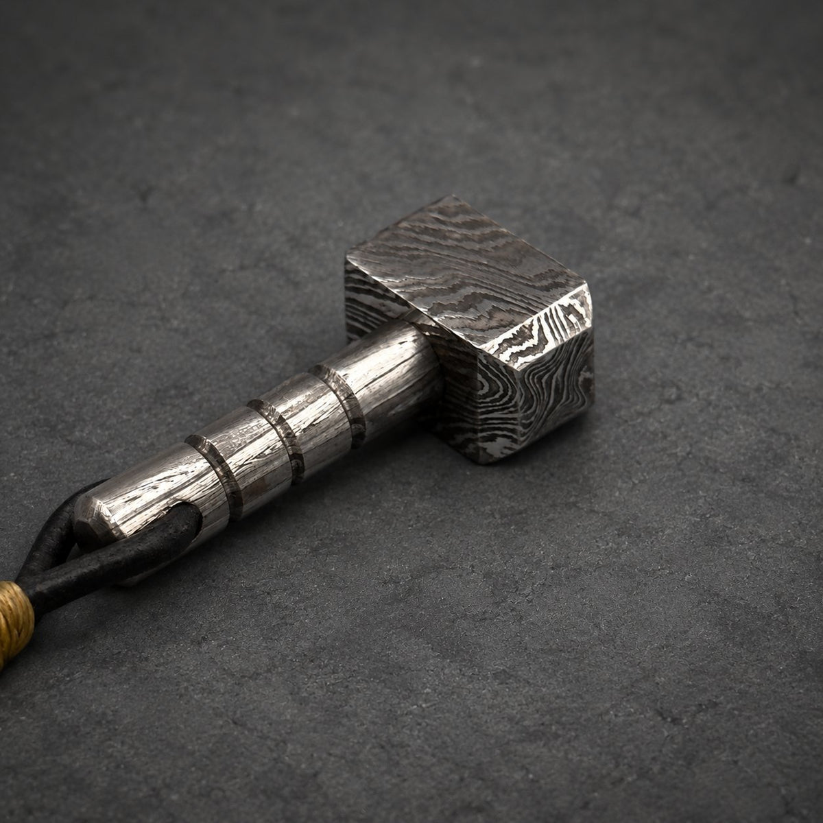 Damascus steel Thor hammer keychain laid flat, showing the banded handle