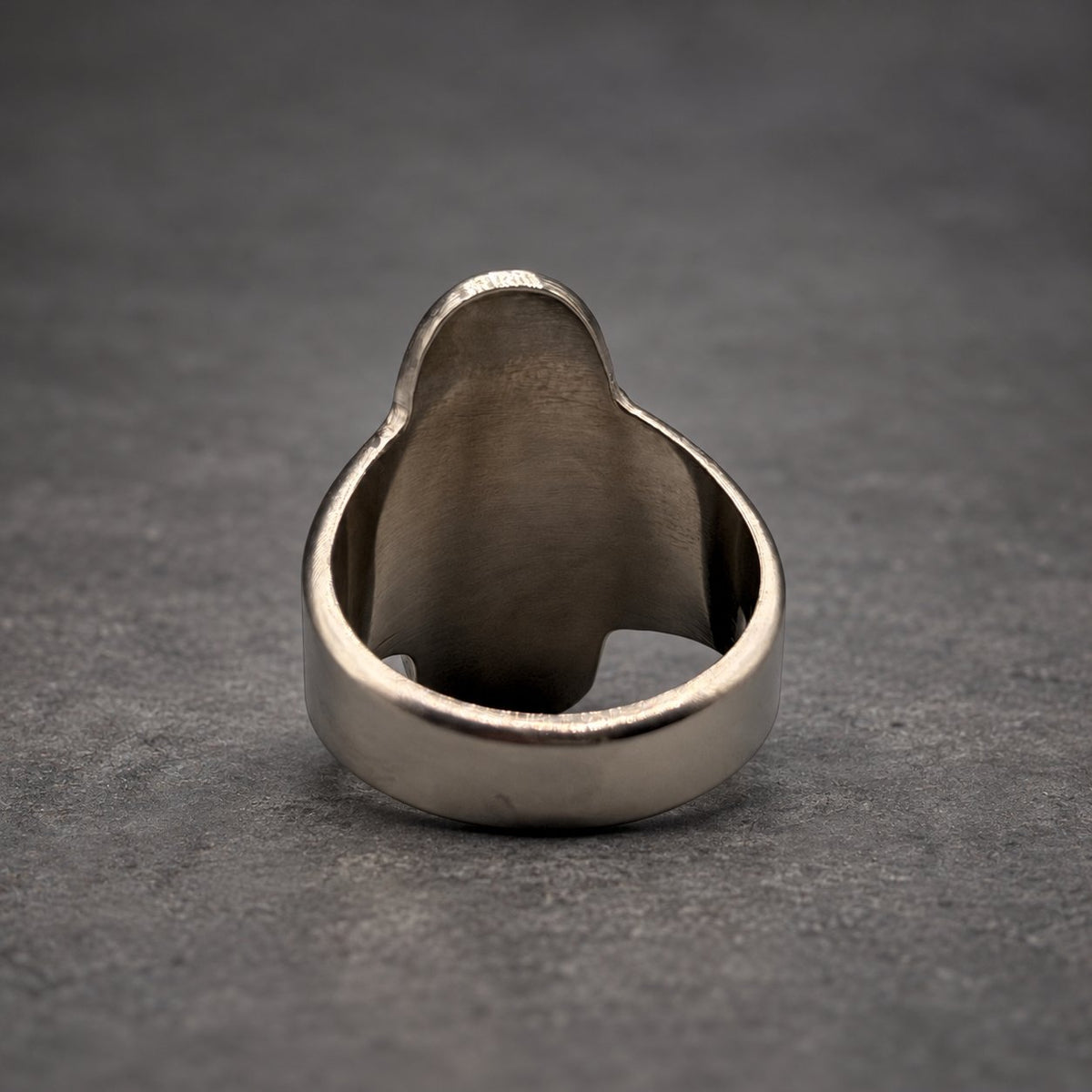 A stainless steel ring with a rounded, elongated face. The ring has a smooth, polished finish and a wide band. The design is simple and modern, suitable for everyday wear. The ring is shown against a neutral background.